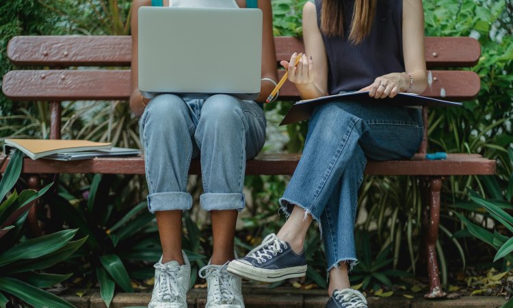 benen-van-2-personen-op-een-bankje-die-met-laptop-en-notities-aan-het-overleggen-zijn