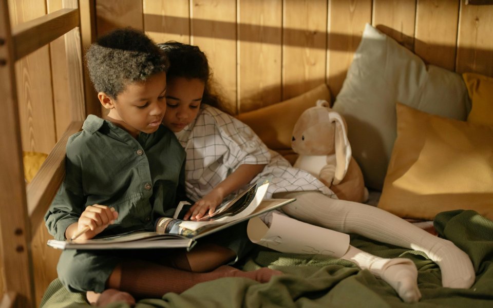 2-kinderen-liggen-samen-in-een-hoekje-te-lezen