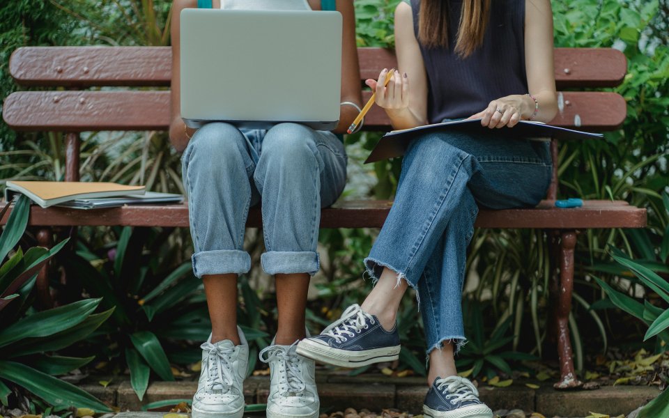 benen-van-2-personen-op-een-bankje-die-met-laptop-en-notities-aan-het-overleggen-zijn