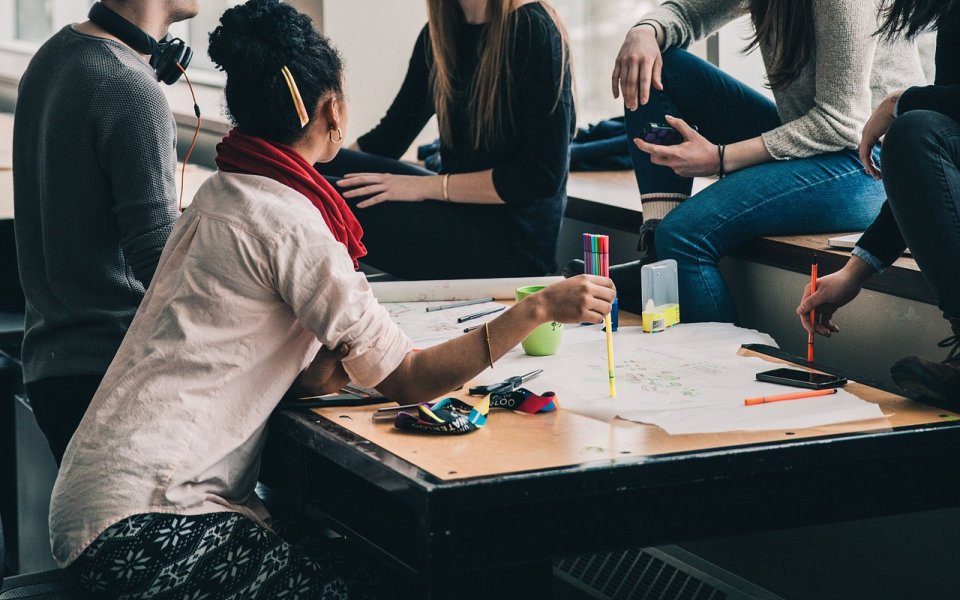 5 jonge mensen rond een bureau