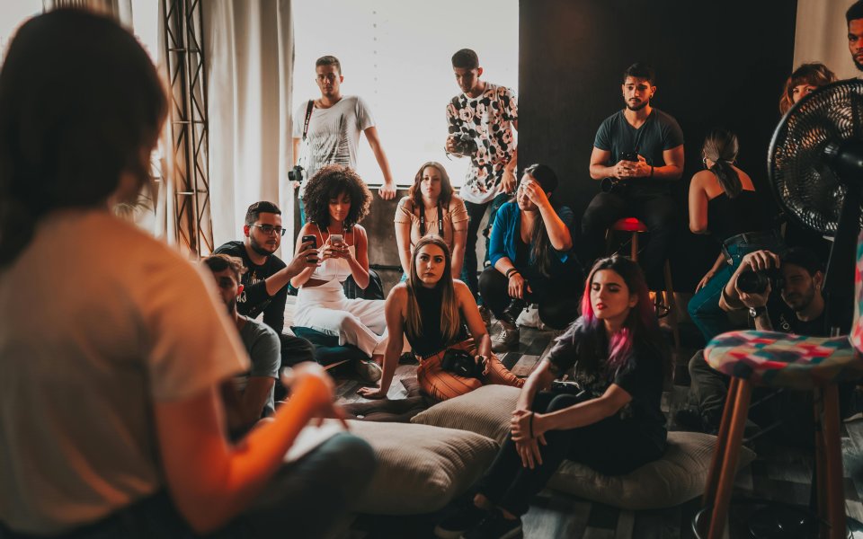 groep-mensen-zit-luisterend-naar-een-verteller-op-de-grond