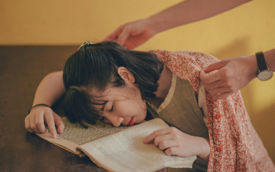 iemand-legt-een-warme-trui-over-schouders-van-slapend-persoon-met-hoofd-op-haar-boeken