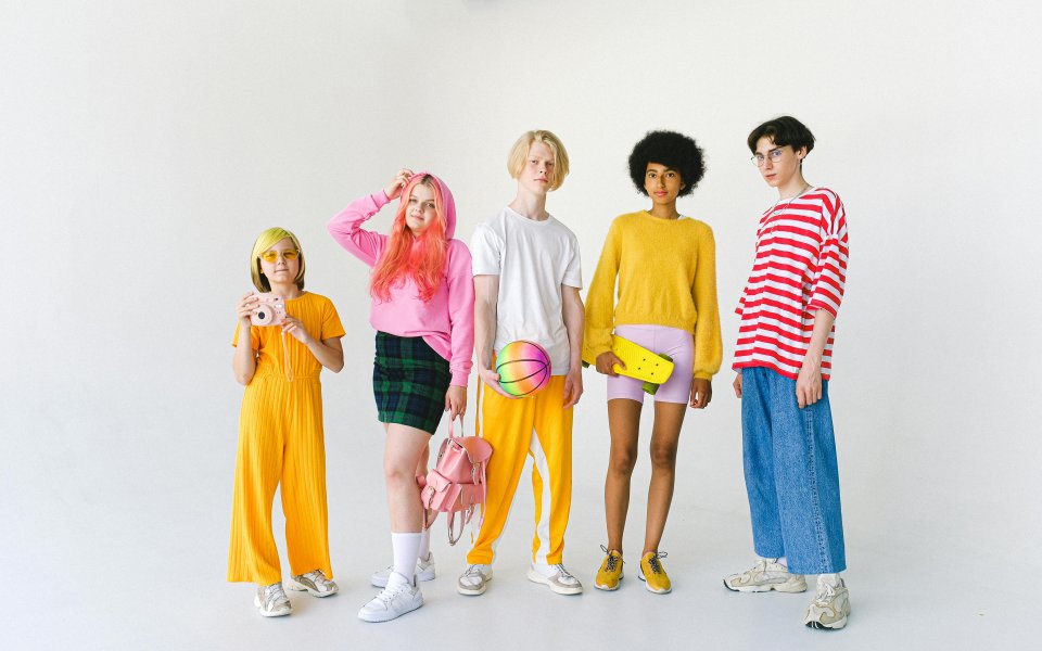 5 kleurig geklede jongeren poseren op een rij