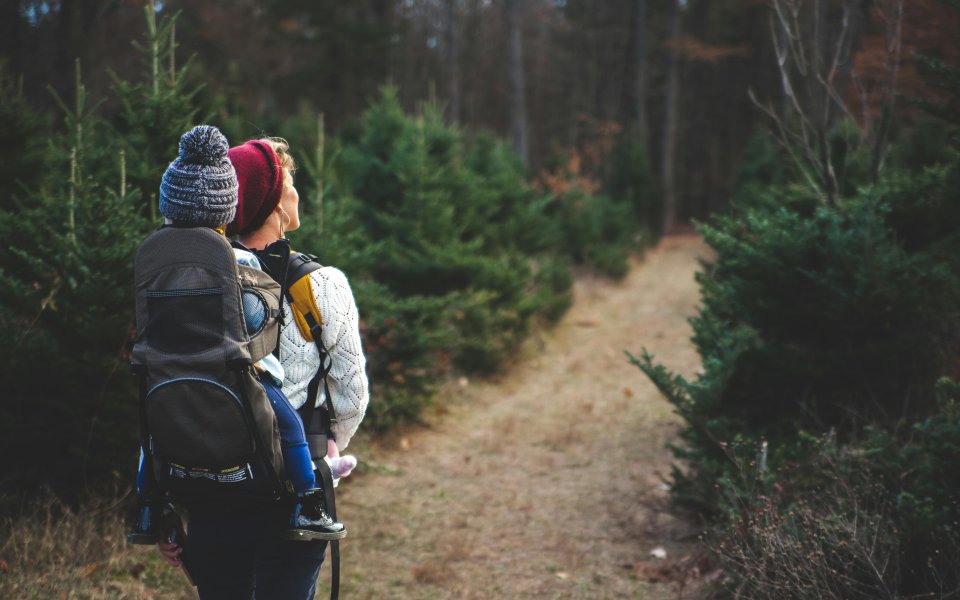 moeder-met-kind-in-rugzak--wandelend-door-een-bos