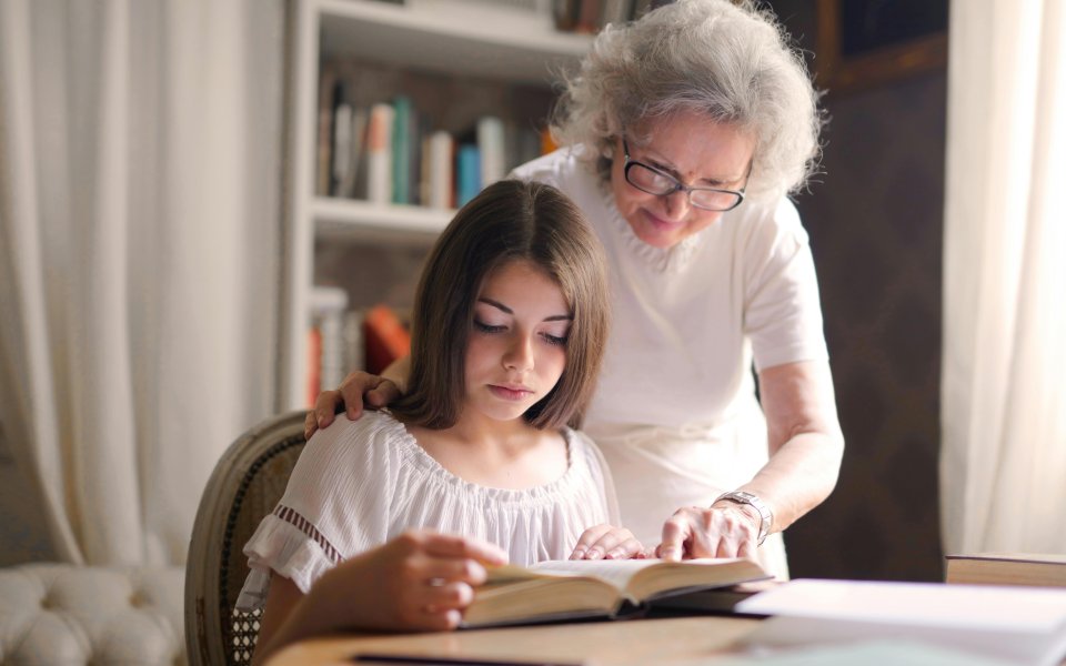 oudere-vrouw-helpt-jong-meisje-bij-huiswerk