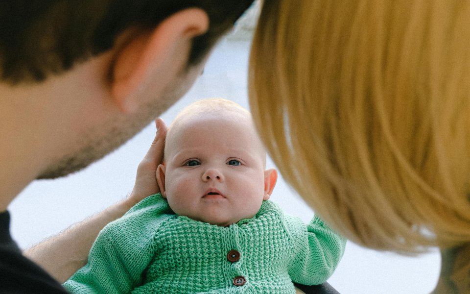 ouders-kijken-naar-baby-die-ze-voor-zich-houden