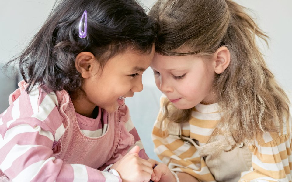 2 peutermeisjes lachen en fluisteren