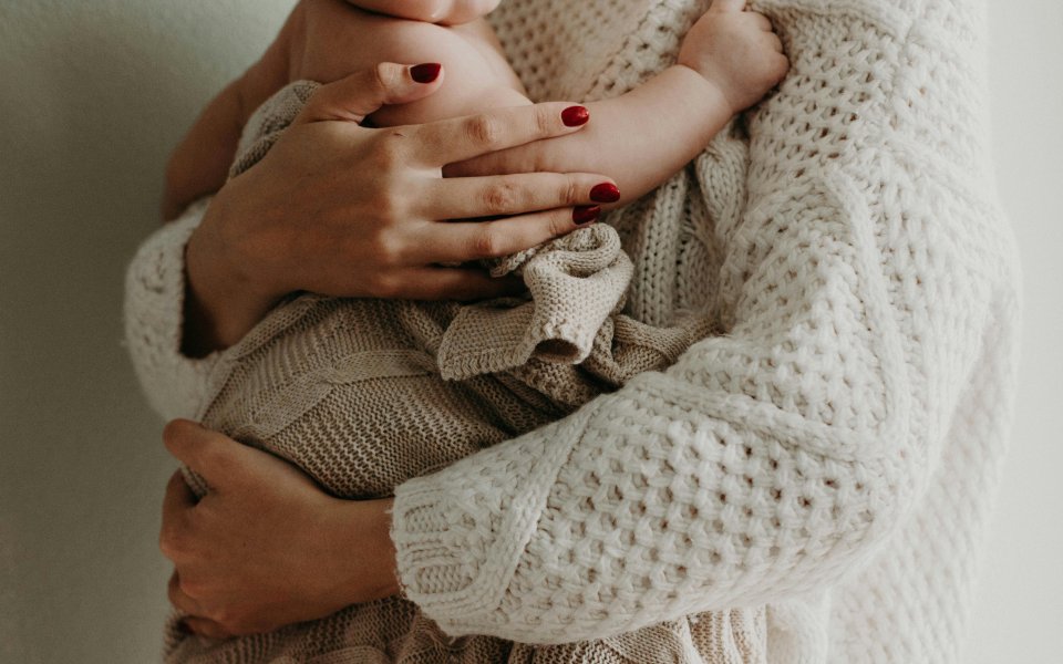 handen van moeder die baby dicht bij zich houdt