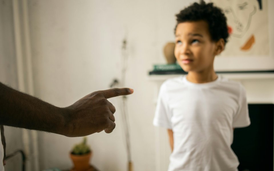 vinger-wijst-naar-kind--dat-op-de-achtergrond-onzeker-opkijkt