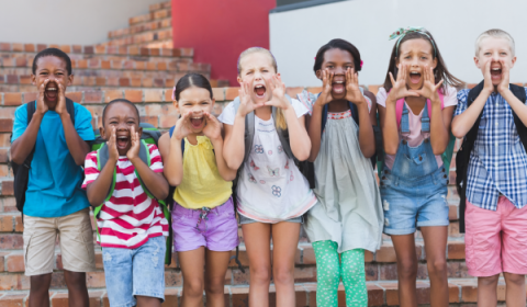 Groep kinderen staat op een rij en roept met de handen voor de mond